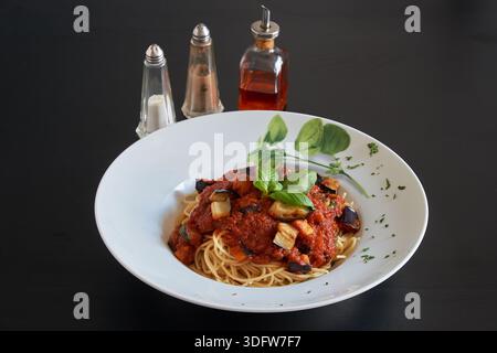 Ein Teller Spaghetti Melanzana Nudeln auf einem schwarzen Holztisch Stockfoto