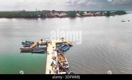 Luftaufnahme eines Piers, der sich in das glitzernde Wasser erstreckt, um ihn herum geballte Boote, die den Himmel reflektieren, Kaa Waterfront, Khana, Bori, Nigeria. Stockfoto
