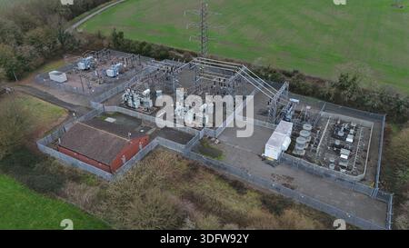 Luftaufnahme einer elektrischen Umspannstation mit Transformatoren und Stromleitungen, die sich stark gegen die grüne Landschaft erheben, Melton Mowbray, England, Unite Stockfoto