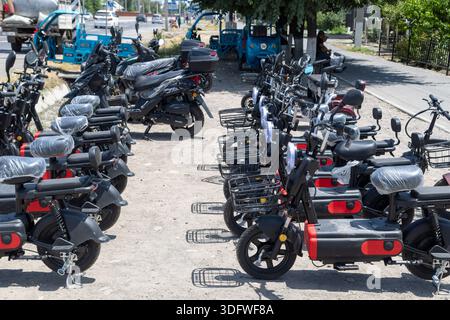 Chinesische Elektroroller und Motorräder werden am 23. Juni 2024 auf der sonnigen Sommerstraße in Sokuluk, Kirgisistan, verkauft Stockfoto
