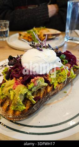 Ein gesundes Stück geröstetes Brot, garniert mit cremiger Avocado und einem perfekt gekochten Ei für ein ausgewogenes, nährstoffreiches Frühstück. Diese Seite Stockfoto