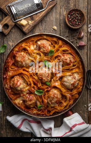 Fleischbällchen in Nudelnestern mit Tomatensauce, Blick von oben, hölzerner Hintergrund Stockfoto