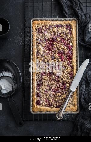 Kirsch- und Mandel-Streuseltorte, schwarzer Hintergrund, Draufsicht Stockfoto