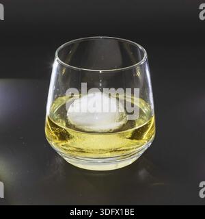 Whiskey auf den Felsen in einem runden Trinkglas als Studioaufnahme mit schwarzem Hintergrund Stockfoto