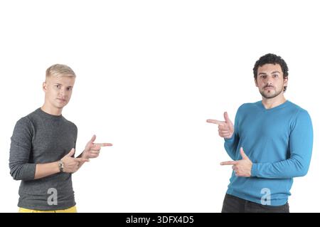 Zwei schöne Jungs irgendwo mit Fingern zeigen, isoliert auf weißem Stockfoto
