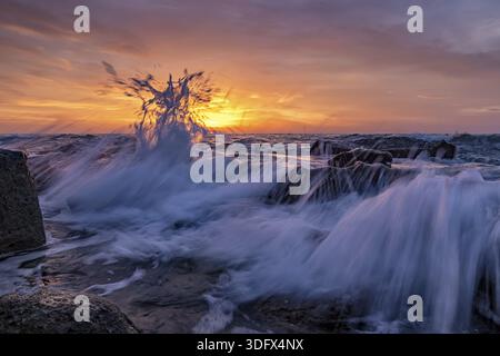 Erstaunliches Meerwasser bei Sonnenaufgang am Ufer des Schwarzen Meeres. Wunderschöne Bewegungen verwischen Meereswellen über den Felsen. Low-Angle-Ansicht Stockfoto