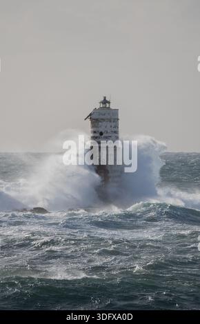 Mächtige Meereswellen, die bei intensivem Seesturm gegen einen Leuchtturm krachen Stockfoto