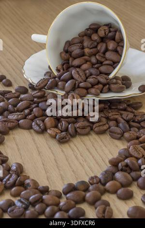 Morgenherz. Herzform aus Kaffeebohnen und einer Tasse Kaffee mit Bohnen Stockfoto