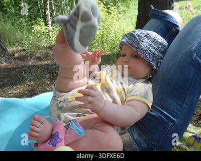 Baby in Sonnenhut spielt draußen mit Spielzeug Stockfoto