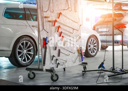 Ein gut organisierter Satz von Werkzeugen, die für die Detaillierung und Reparatur von Fahrzeugen verwendet werden, wird in einer Garage ausgestellt. In der Nähe befindliche Fahrzeuge werden gerade gewartet und Stockfoto
