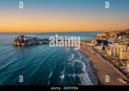 Aus der Vogelperspektive auf eine sonnige Küstenstadt zur goldenen Stunde, mit einem geschwungenen Sandstrand, Peniscola, Spanien Stockfoto