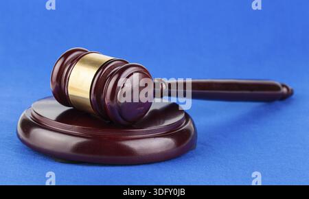 Hölzerner brauner Richter-Hammer auf blauem Hintergrund Stockfoto