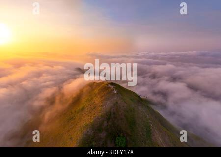 Morgenlicht von der Sonnenaufgang an der Küste mit Bergen und Hügeln, die von nassen Wolken und Nebel umhüllt sind, warme Sommertöne, die über dem Point View Landc liegen Stockfoto