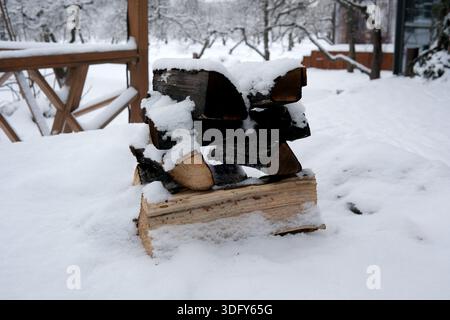 In einer friedlichen Winterlandschaft liegt das Feuerholz unter einer weichen Schneedecke. Stockfoto