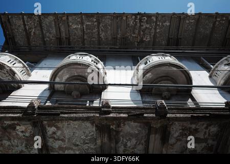 Flacher Blick auf die verwitterte klassische Fassade mit geschwungenen Balkonen und Drähten Stockfoto