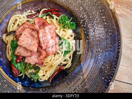 Spaghetti heiß und würzig mit gegrilltem Schinken, Basilikum und Chili auf Keramikplatte Stockfoto