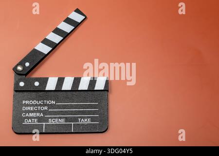 Klemmbrett auf orangefarbenem Hintergrund, das das Filmemachen und den Beginn eines Films darstellt. Stockfoto