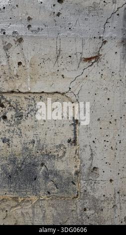 Strukturierte Betonwand mit Rissen und Flecken Stockfoto