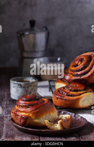 Hefeteig mit Zimt mit Mohnsamen, Rosinen und kandierten Früchten, serviert mit Kaffee. Rustikaler Stil. Stockfoto