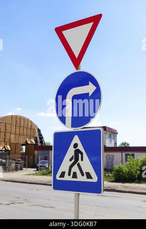 Triangular, Runde und quadratische Verkehrszeichen vor blauem Himmel Stockfoto