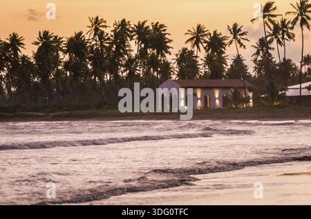 Sao Miguel dos Milagres, Brasilien - 16. November 2019: Wunderschönes Bild des Strandes von Sao Miguel dos Milagres mit seiner berühmten Kirche bei Sonnenuntergang Stockfoto