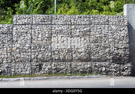 Schutz Zaun oder Mauer aus gabionen mit Steinen. Steinmauer mit Metallgitter als Hintergrund. Stein -Textur Stockfoto