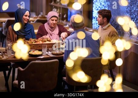 Die muslimische Familie genießt iftar gemeinsam in einem Restaurant, das für Ramadan-Feiern eingerichtet ist Stockfoto
