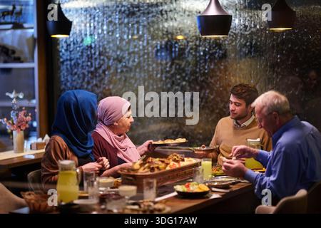 Familie genießt iftar in einem Restaurant während des Ramadan mit Dekoration und warmer Beleuchtung Stockfoto