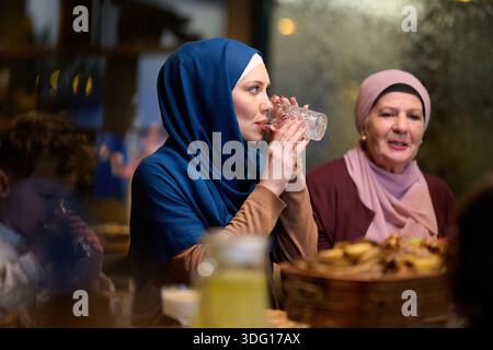 Die muslimische Familie genießt iftar gemeinsam in einem Restaurant mit Ramadan-Dekoration und warmer Beleuchtung Stockfoto