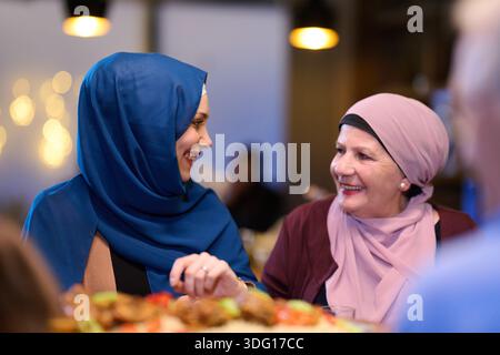 Die muslimische Familie genießt iftar gemeinsam in einem Restaurant mit Ramadan-Dekoration und warmer Beleuchtung Stockfoto