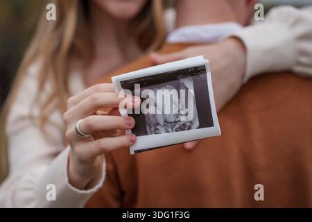 Ein schwangeres Mädchen umarmt ihren Mann und hält ein Foto von den Uzi in der Hand Stockfoto