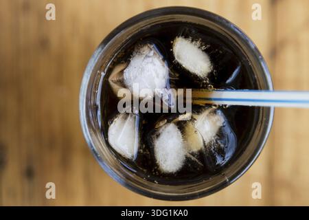 Limonade Glas mit Eiswürfeln und Stroh auf Holztisch Stockfoto