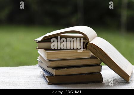 Stapel Bücher auf dem Tisch im Garten mit geöffnetem Oberteil Stockfoto