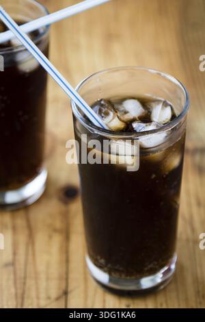 Limonade Glas mit Eiswürfeln und Stroh auf Holztisch Stockfoto
