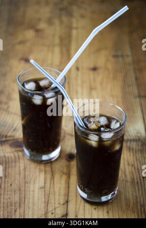 Limonade Glas mit Eiswürfeln und Stroh auf Holztisch Stockfoto