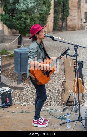 Barcelona, Spanien - 20. Oktober 2025: Eine Straßensoministin spielt Gitarre auf der Plac de la Seu in der Nähe der Kathedrale von Barcelona. Stockfoto
