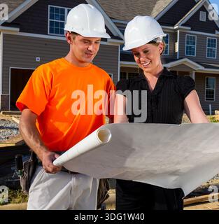 Auf einer sonnendurchfluteten Baustelle studieren ein Bauarbeiter und ein Ingenieur gemeinsam Blaupausen, messen Linien und besprechen Details, während sich der Rahmen erhöht, Team Stockfoto