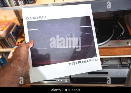 Paris, Frankreich - 9. September 2025: A Hand präsentiert die Diana Krall This Dream of You audiophile LP in ihrer Schrumpffolie, die über einem Plattenspieler und Regalen gehalten wird Stockfoto