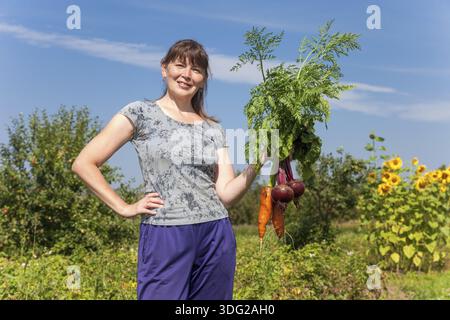 Junge Frau, die eine Garbe von Gemüse in der Hand halten Stockfoto