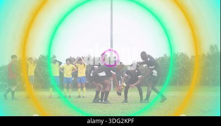 Forming Scrum Cluster männliche Spieler in schwarz Hocken auf dem Rasenfeld mit Rugbyball, Farbringe Stockfoto