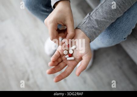 Die beschnittene unglückliche europäische depressive Millennial Lady hält viele Pillen in der Hand und denkt an Selbstmord, von oben Stockfoto