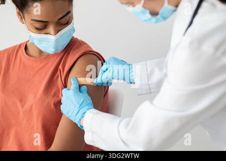 Krankenschwester, die medizinischen Pflaster auf den weiblichen Patientenarm legt Stockfoto