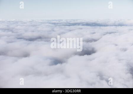 Die ruhige Aussicht aus der Luft zeigt eine dichte Decke aus weißen Wolken, die sich endlos unter einem hellen Himmel erstreckt. Weiche Textur und dezente Schatten sorgen für Ruhe Stockfoto