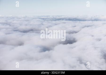 Die ruhige Aussicht aus der Luft zeigt eine dichte Decke aus weißen Wolken, die sich endlos unter einem hellen Himmel erstreckt. Weiche Textur und dezente Schatten erinnern an Ruhe, Altitu Stockfoto