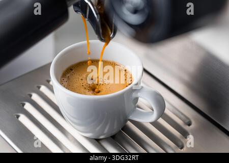 Espresso, der auf einer Heimmaschine in eine Tasse gebrüht wird Stockfoto