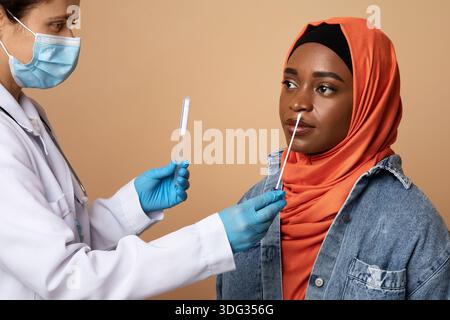 Medizinisches Personal, das einen Tupfer für eine Coronavirus-Probe von einer muslimischen Frau nahm Stockfoto