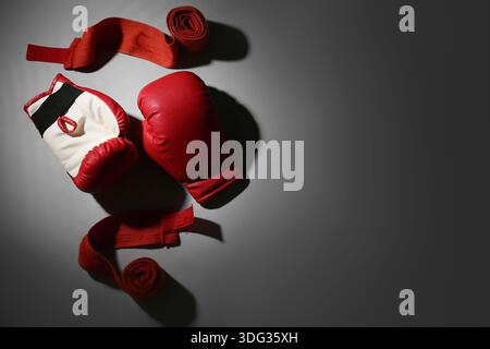 Rote Boxhandschuhe mit Armbändern auf grauem Hintergrund Stockfoto