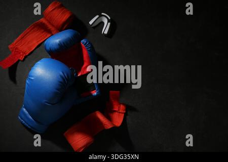 Ein Paar blaue Boxhandschuhe mit Armbändern und Mundstück auf schwarzem Hintergrund Stockfoto