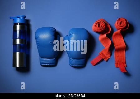 Boxhandschuhe mit Armbändern und Flasche Wasser auf blauem Hintergrund Stockfoto