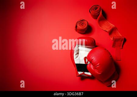 Ein Paar Boxhandschuhe mit Armbändern auf rotem Hintergrund Stockfoto